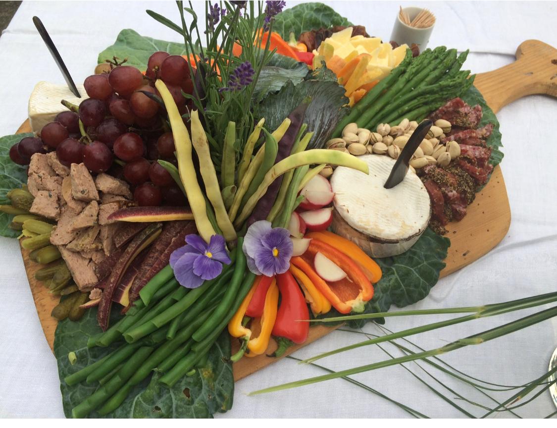 Lavish garden charcuterie board with pâté, grapes, pistachios, and edible flowers