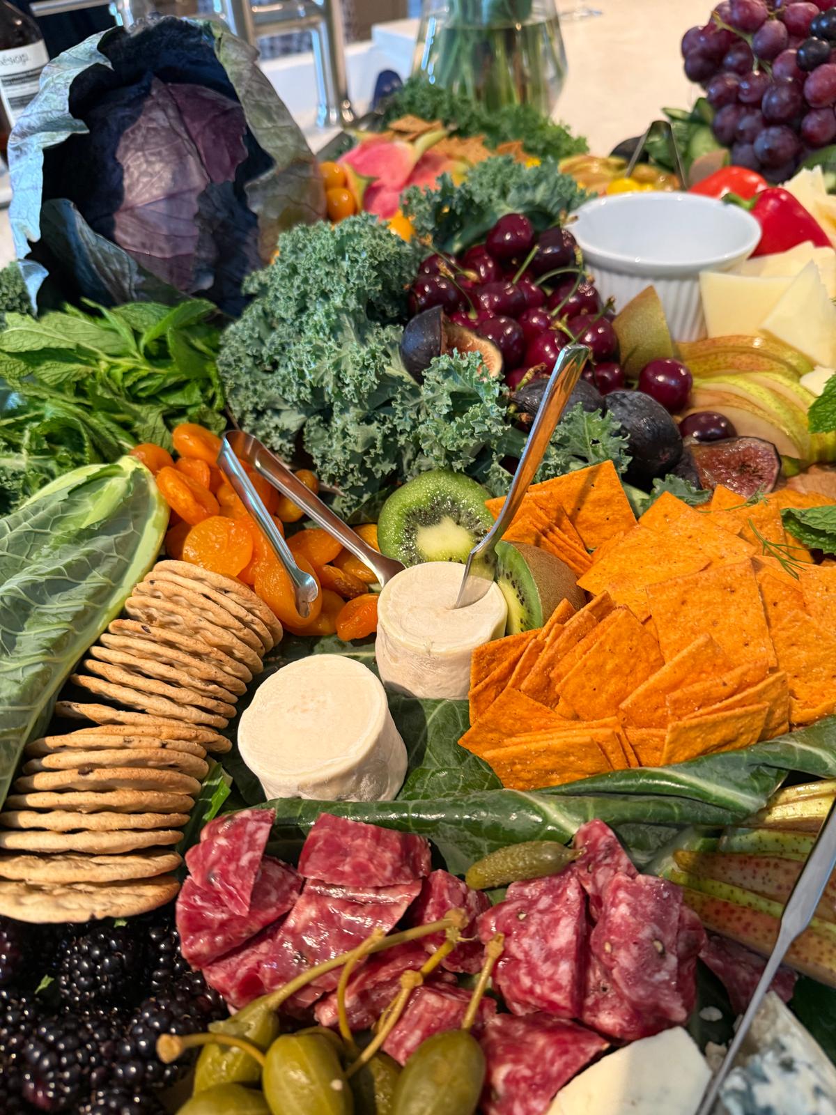 Lush grazing table with charcuterie, cheeses, fruit, and crackers