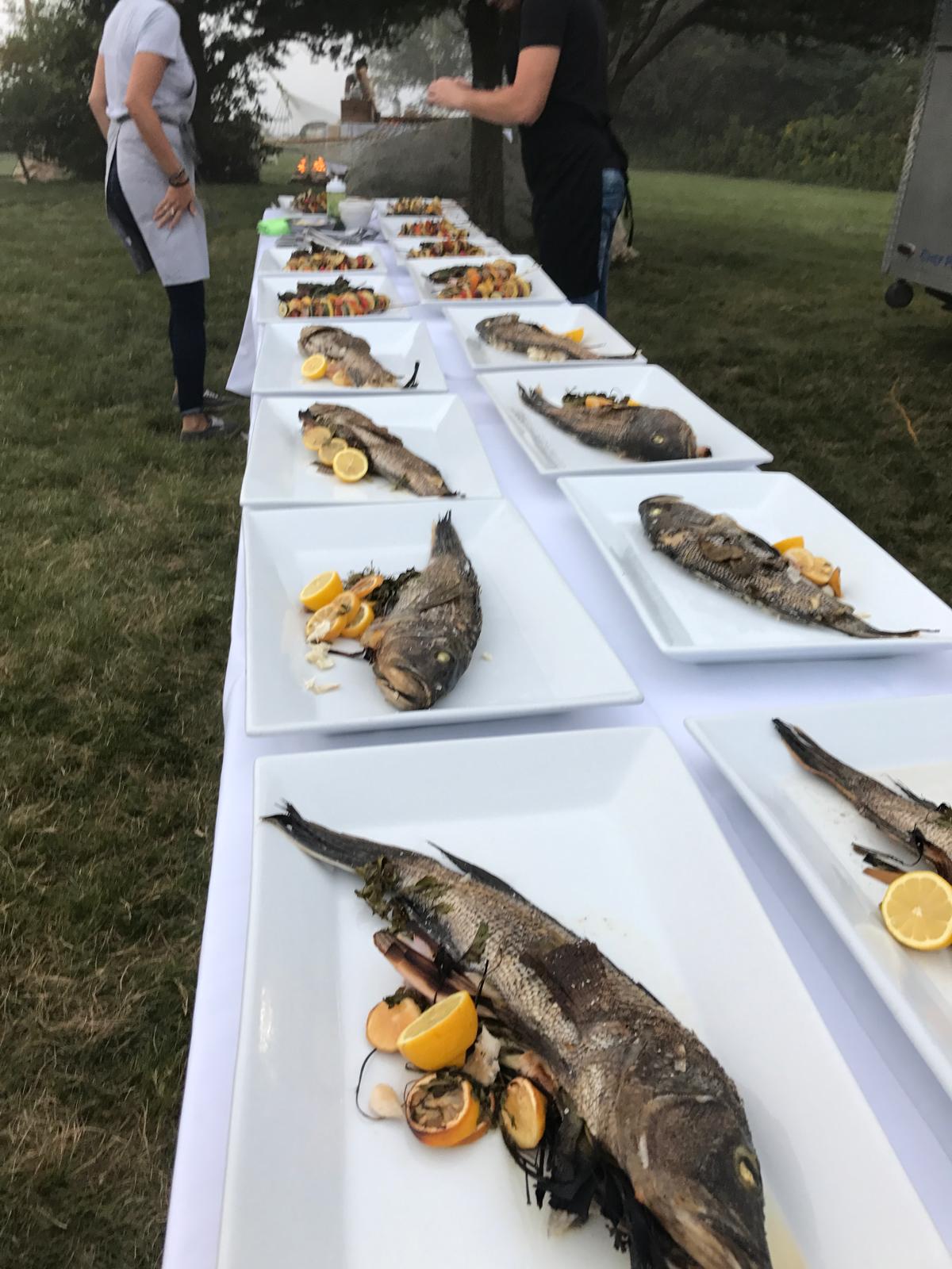 Whole grilled fish plated for a long outdoor dinner