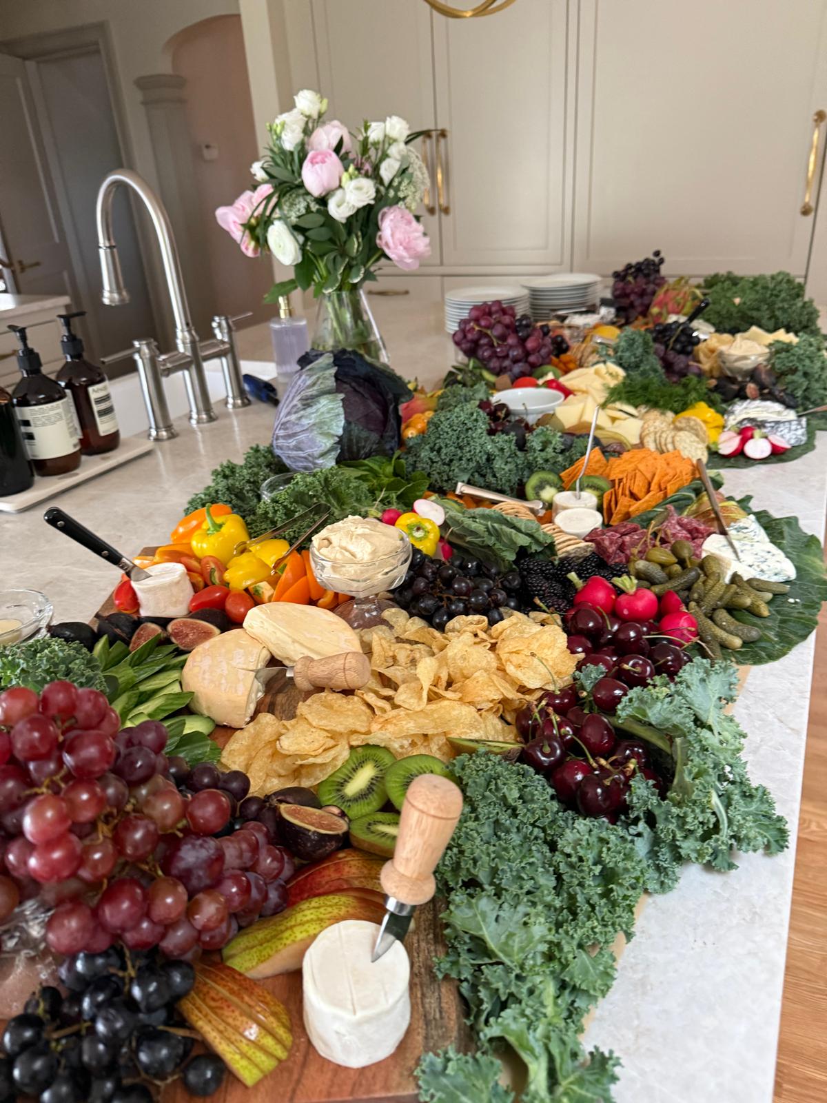 Abundant grazing board with cheeses, fruit, and flowers